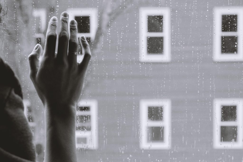 girl putting hand against window dark