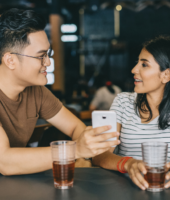 girl sitting down with boyfriend showing something on his phone