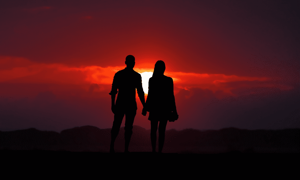 couple holding hands against the sunset