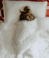 girl hiding under blankets
