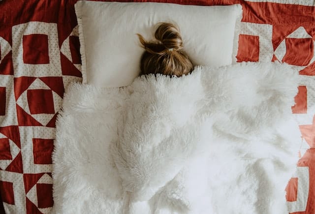 girl hiding under blankets